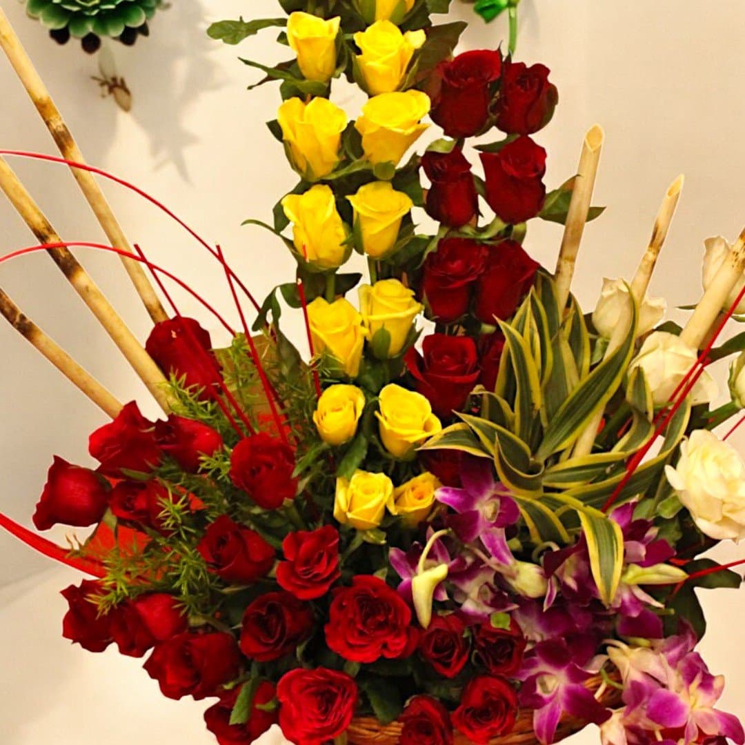 Close-up shot of Beautifully arranged mix of roses and orchids in a basket by BetterGiftFlowers.