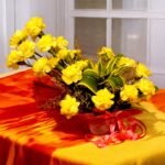 Yellow carnations bouquet from BetterGiftFlowers, beautifully arranged with lush green leaves in a decorative basket, perfect for gifting.